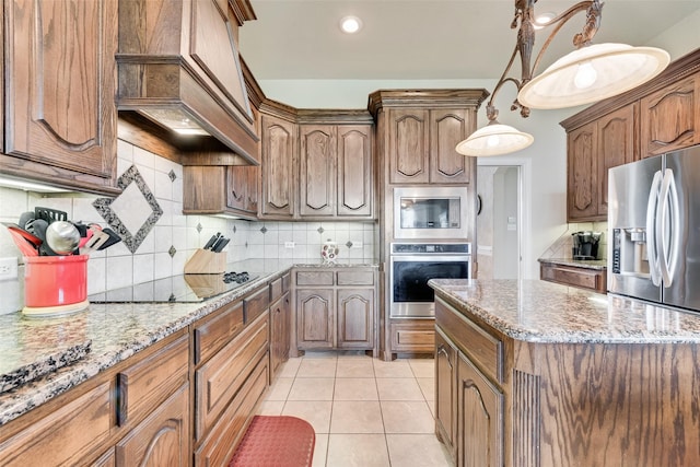 kitchen with light stone counters, custom exhaust hood, decorative backsplash, a kitchen island, and appliances with stainless steel finishes
