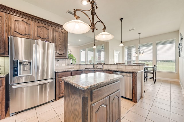 kitchen with a center island, light tile patterned flooring, a sink, a peninsula, and stainless steel appliances