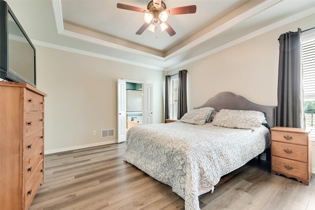 bedroom with a tray ceiling, baseboards, ceiling fan, visible vents, and light wood-style floors