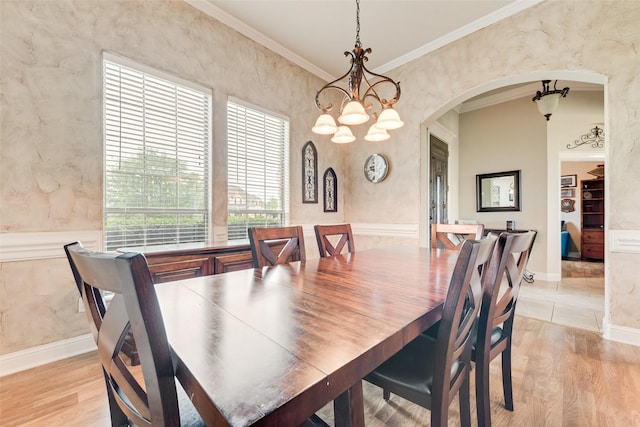 dining area featuring crown molding, light wood-style flooring, a notable chandelier, and arched walkways