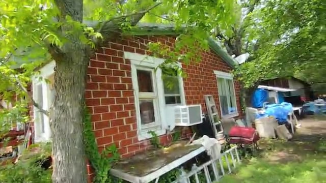 view of property exterior with cooling unit and brick siding