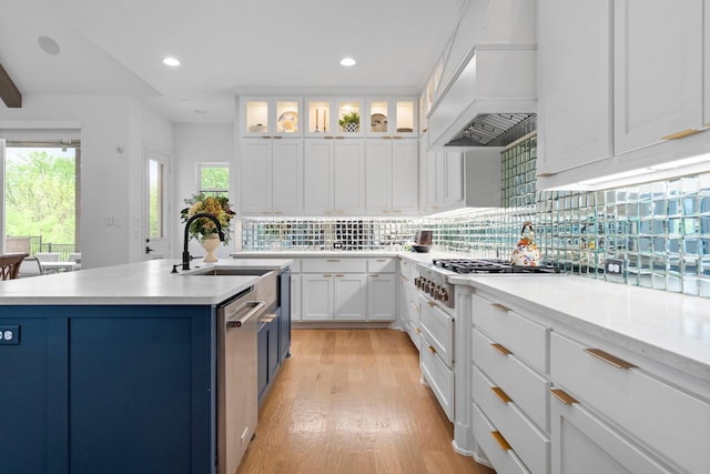 kitchen featuring custom exhaust hood, white cabinetry, light countertops, and light wood finished floors