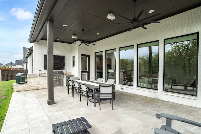 view of patio with outdoor dining space, area for grilling, fence, ceiling fan, and a sink