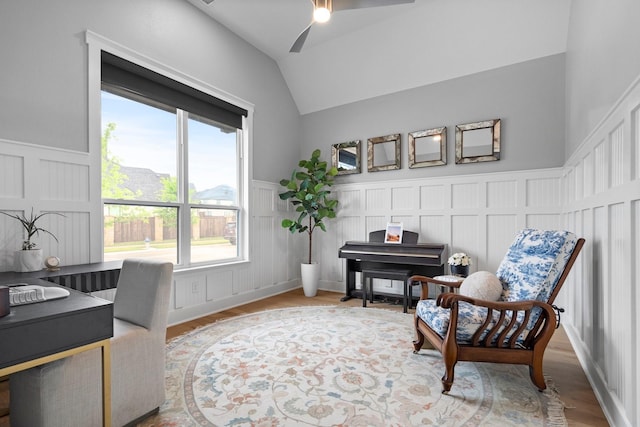 sitting room featuring vaulted ceiling, a decorative wall, a wainscoted wall, and a ceiling fan