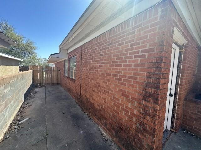 view of side of property with brick siding and fence