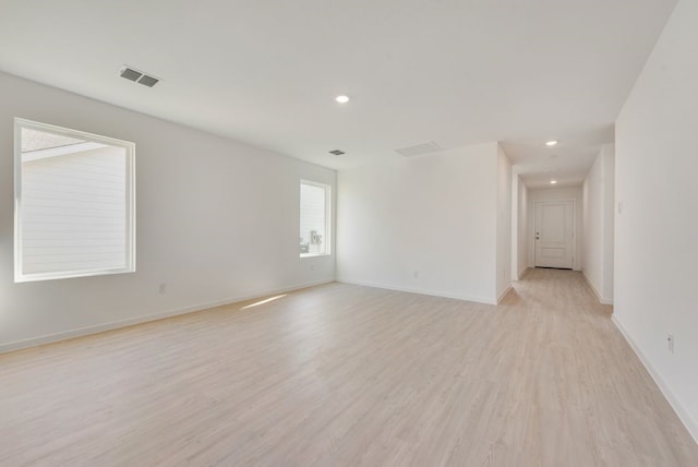 empty room with light wood-style floors, visible vents, baseboards, and recessed lighting