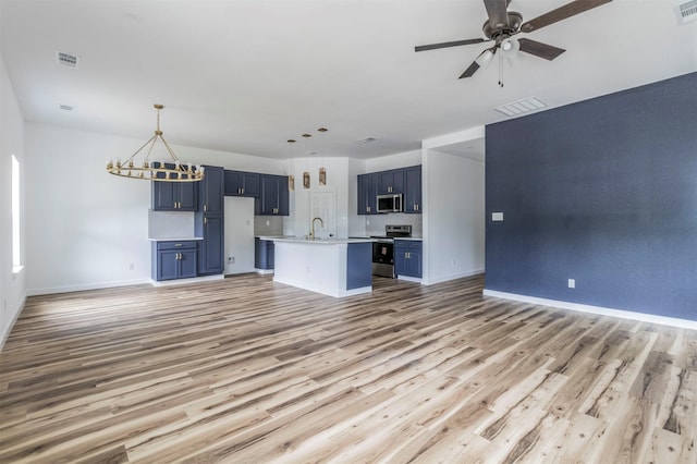 1014 Trinity St, Cleburne, TX 76031 - unfurnished living room featuring light wood-style flooring, a sink, baseboards, a ceiling fan, and a chandelier