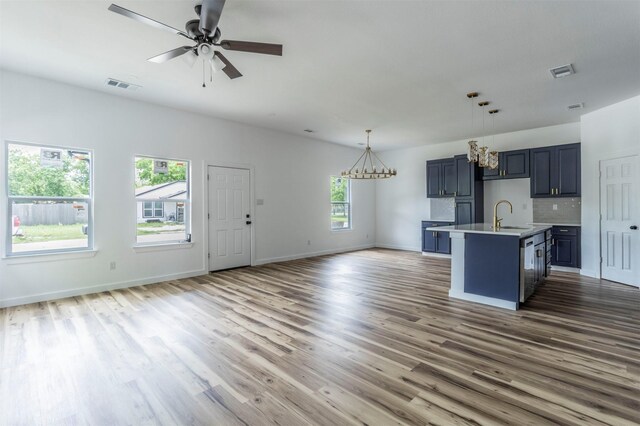 1014 Trinity St, Cleburne, TX 76031 - kitchen featuring open floor plan, a chandelier, a sink, light countertops, and wood finished floors