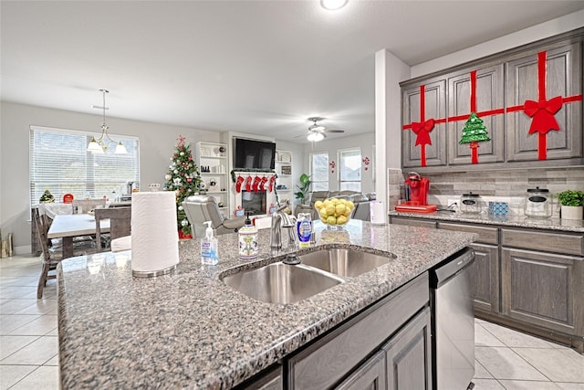 kitchen with a sink, plenty of natural light, stainless steel dishwasher, ceiling fan, and light tile patterned flooring