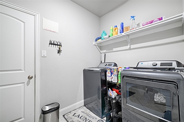 clothes washing area featuring laundry area, baseboards, and washer and dryer