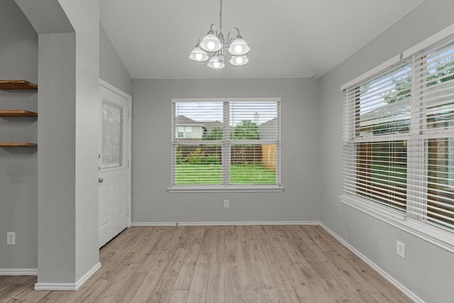 unfurnished dining area with a notable chandelier, light wood finished floors, and plenty of natural light