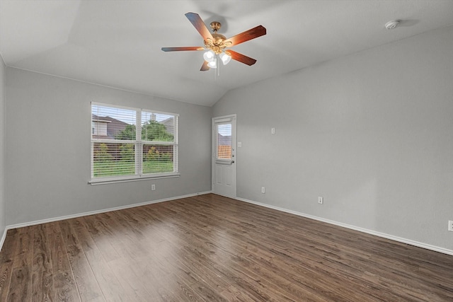 spare room featuring dark wood-style flooring, lofted ceiling, baseboards, and ceiling fan