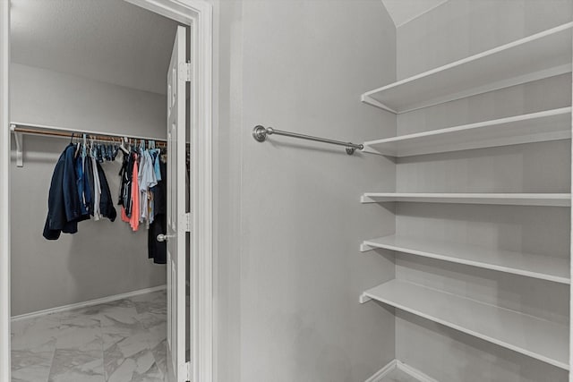 walk in closet featuring marble finish floor