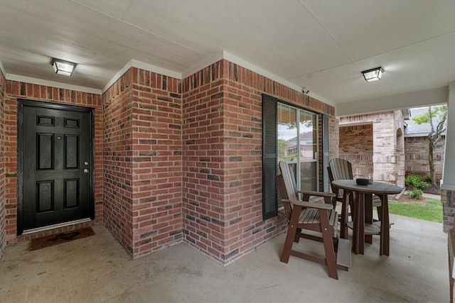 entrance to property featuring brick siding and covered porch