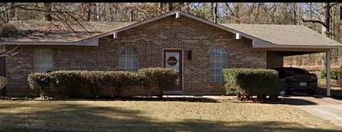 ranch-style house featuring a carport, a front lawn, brick siding, and driveway