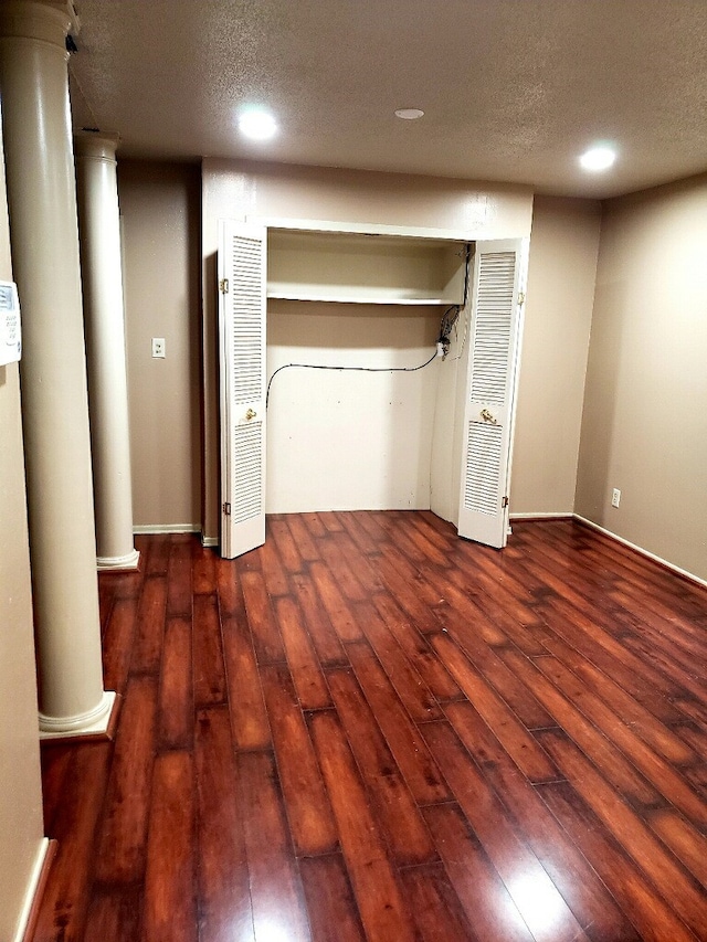 unfurnished bedroom featuring wood-type flooring, a textured ceiling, recessed lighting, and decorative columns