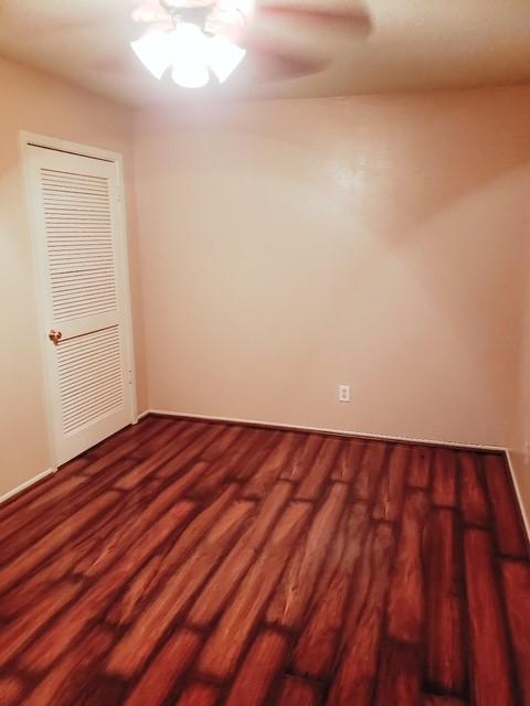 spare room with dark wood-type flooring and a ceiling fan