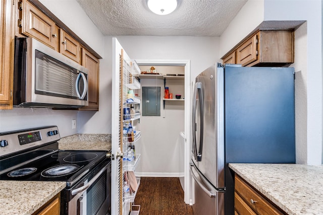 1200 Harwell Dr Unit 1924, Arlington, TX 76011 - kitchen featuring appliances with stainless steel finishes, a textured ceiling, brown cabinetry, dark wood finished floors, and baseboards