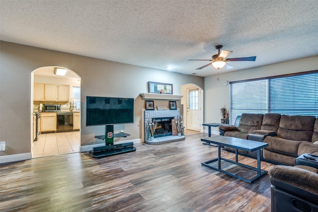 6109 Sasaki Way, Garland, TX 75043 - living area with light wood finished floors, arched walkways, baseboards, a ceiling fan, and a fireplace