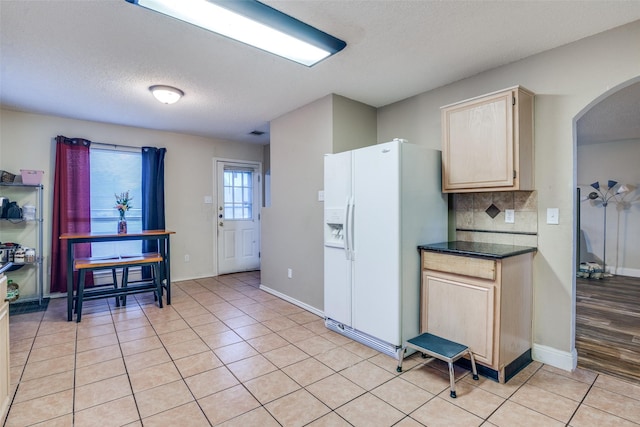6109 Sasaki Way, Garland, TX 75043 - kitchen with white fridge with ice dispenser, arched walkways, a textured ceiling, dark countertops, and light tile patterned floors