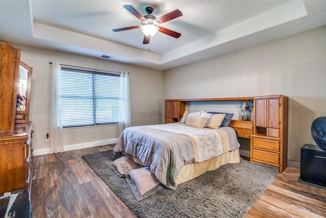 6109 Sasaki Way, Garland, TX 75043 - bedroom featuring a raised ceiling, baseboards, wood finished floors, a textured ceiling, and ceiling fan