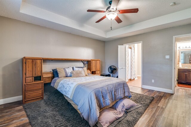 6109 Sasaki Way, Garland, TX 75043 - bedroom with a raised ceiling, baseboards, wood finished floors, and ensuite bath