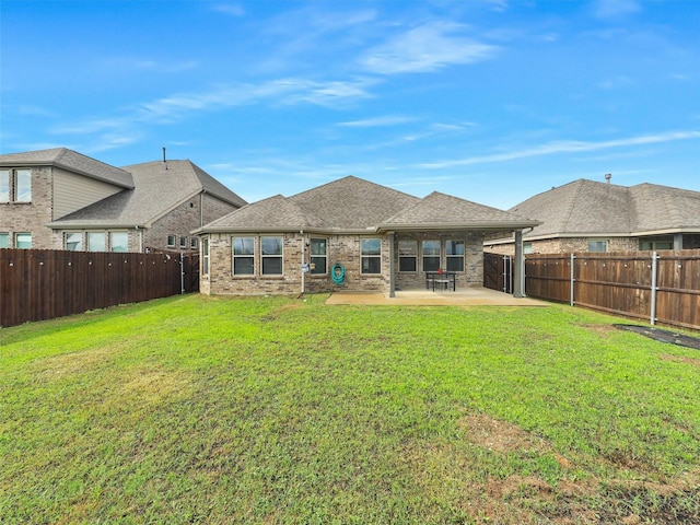 back of property featuring a yard, brick siding, a fenced backyard, and a patio