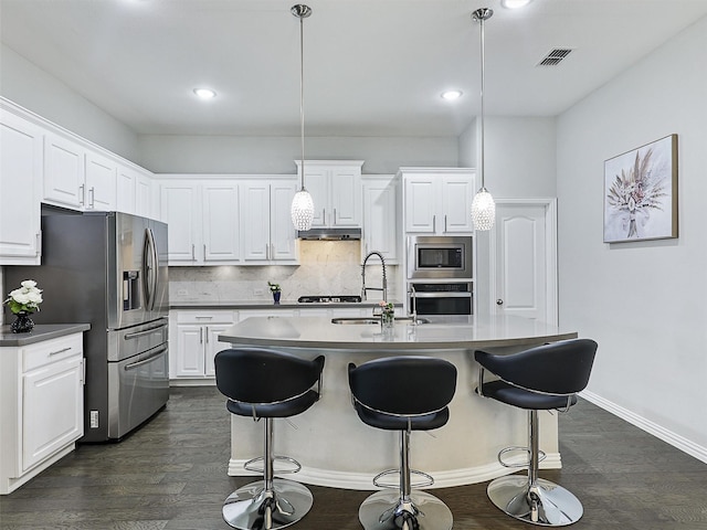 kitchen with stainless steel appliances, white cabinets, under cabinet range hood, tasteful backsplash, and dark wood-style floors