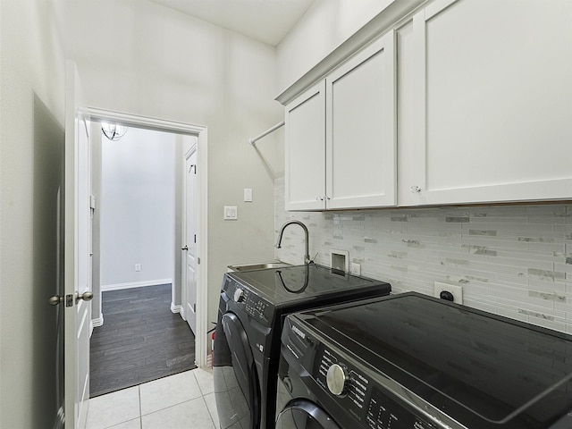 laundry room with a sink, cabinet space, independent washer and dryer, light tile patterned flooring, and baseboards