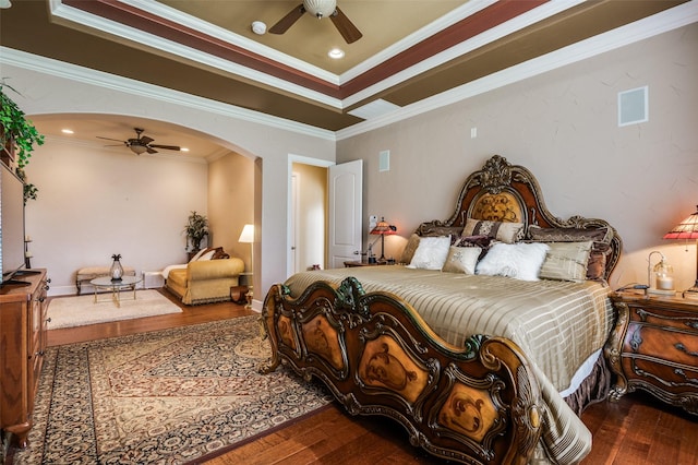 bedroom with crown molding, arched walkways, hardwood / wood-style floors, and a ceiling fan