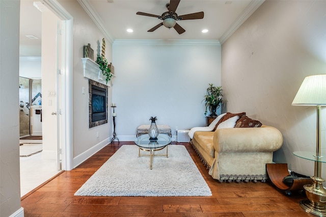 living area featuring wood finished floors, recessed lighting, ceiling fan, crown molding, and a tiled fireplace