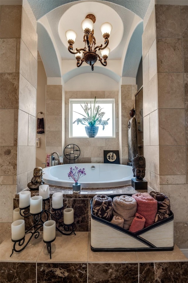 full bath with a bathing tub, tile walls, tiled shower, and a chandelier