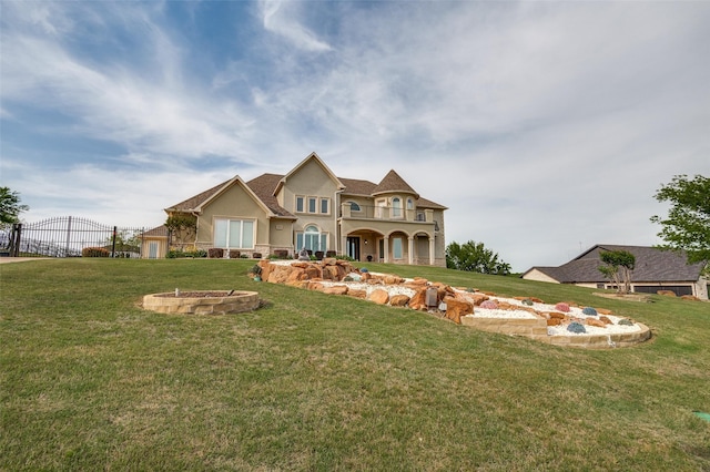 view of front of property featuring a balcony, stucco siding, a fire pit, and a front yard