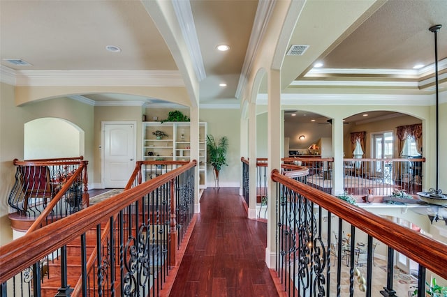 corridor with baseboards, visible vents, crown molding, wood finished floors, and an upstairs landing
