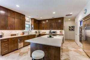 kitchen with stainless steel appliances, recessed lighting, light countertops, a kitchen island, and dark brown cabinets