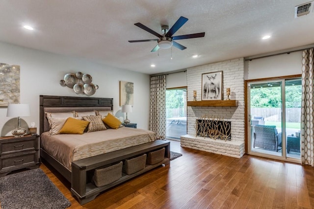 bedroom featuring multiple windows, a brick fireplace, visible vents, and access to exterior