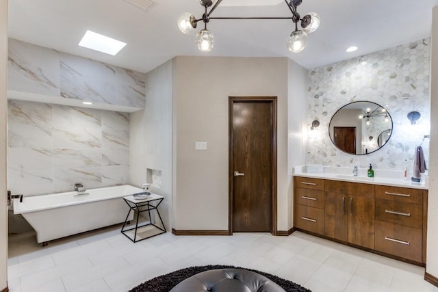 bathroom featuring vanity, baseboards, and a soaking tub
