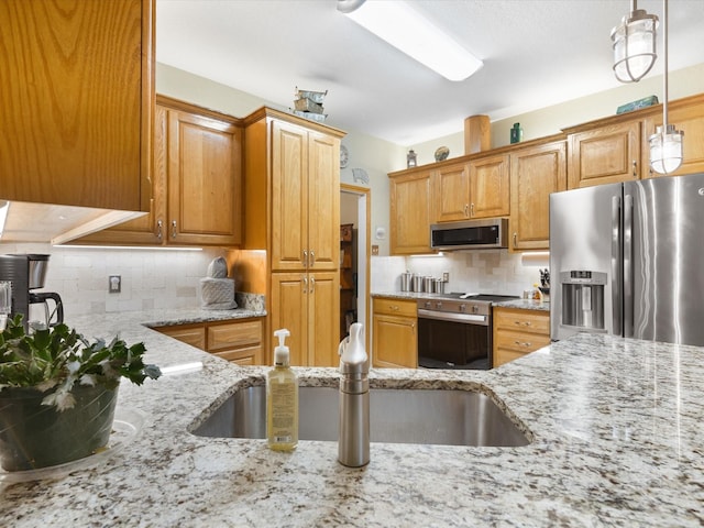 kitchen with a sink, stainless steel appliances, tasteful backsplash, pendant lighting, and light stone countertops
