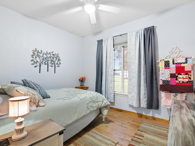 bedroom featuring a ceiling fan, light wood-style flooring, and baseboards