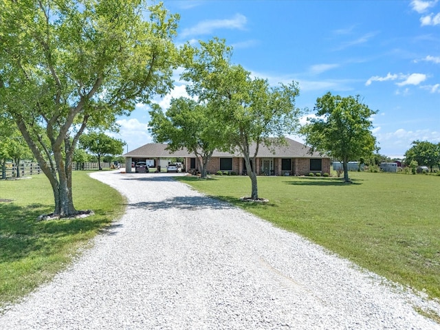 ranch-style home featuring gravel driveway, a front yard, and a carport