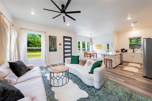 living room with light wood-style floors, visible vents, ceiling fan, and recessed lighting