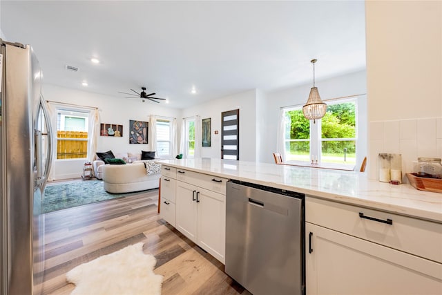 kitchen featuring visible vents, white cabinetry, open floor plan, light stone countertops, and appliances with stainless steel finishes