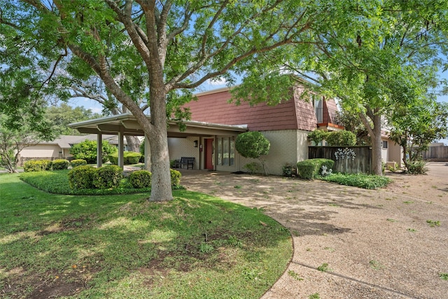 view of front of property with a front lawn, brick siding, and fence