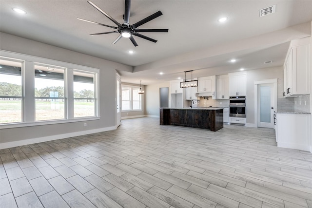 kitchen featuring ceiling fan with notable chandelier, backsplash, open floor plan, and recessed lighting