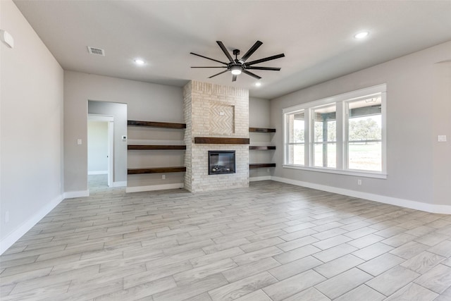 unfurnished living room featuring ceiling fan, a brick fireplace, baseboards, and visible vents