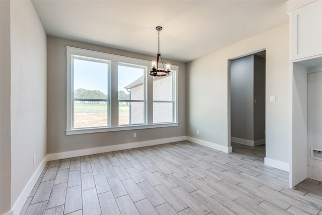 empty room with an inviting chandelier, baseboards, and wood finish floors