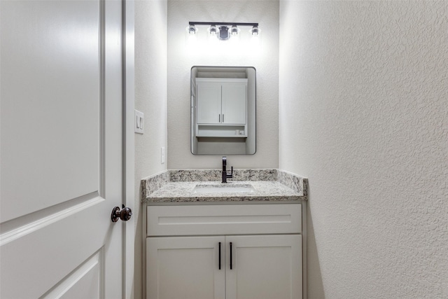 bathroom featuring vanity and a textured wall