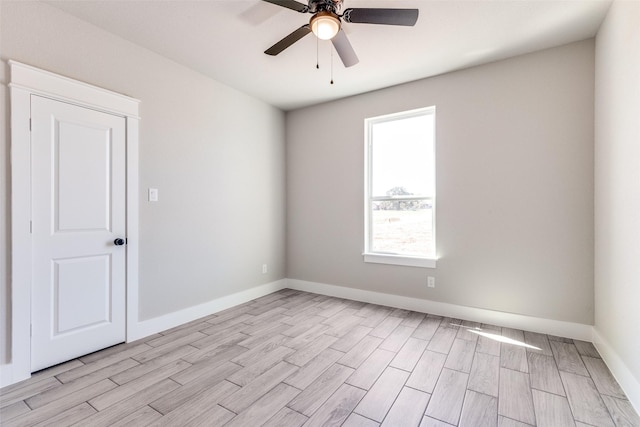 empty room with a ceiling fan, light wood-style floors, and baseboards