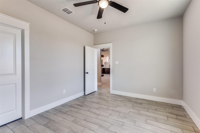 empty room featuring baseboards, ceiling fan, light wood-style floors, and visible vents