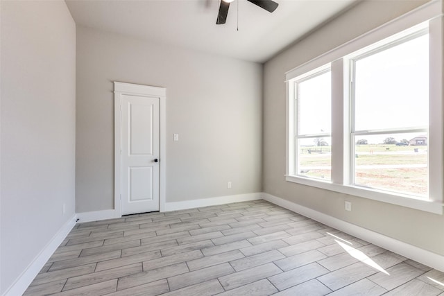 unfurnished room with wood tiled floor, baseboards, and a ceiling fan